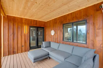 a living room with a couch and a clock on the wall at Brand New Luxury Ski Cabin - 2 Mi to Windham Mtn! in Windham
