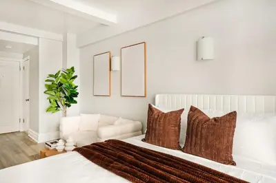 a white bedroom with a white bed with pillows at 73-1004 New Studio UWS Doorman Gym in New York