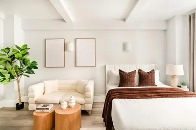 a white bedroom with a bed and a chair at 73-1004 New Studio UWS Doorman Gym in New York