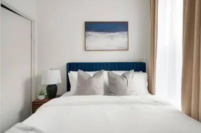 a white bed with a blue headboard and white pillows at 91-2A Stylish 3BR 2Bth with W D in New York