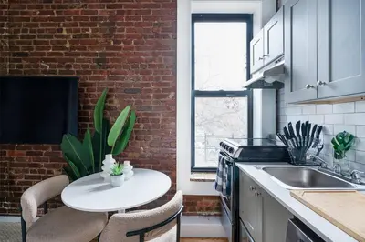 a kitchen with a white table and a brick wall at 153-1G Newly Renovated 2BR Lower East Side in New York