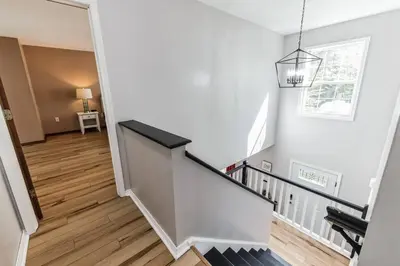 a white staircase with a black handrail in a house at Horatio Hideaway Pocono Escape in Tobyhanna