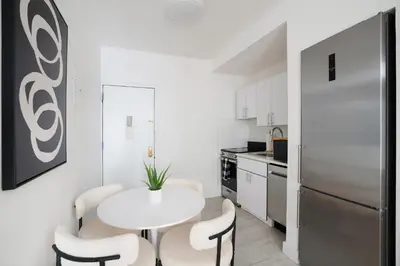 a kitchen with a white table and chairs and a refrigerator at 444-2E Modern 2BR Hell's Kitchen in New York