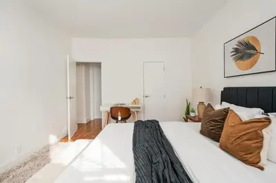 a white bedroom with a large bed with brown pillows at 444-2E Modern 2BR Hell's Kitchen in New York