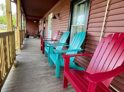 a row of colorful chairs sitting on a porch at 5 Bed / 3 bath Apt Near Jiminy Peak Berkshires in Stephentown