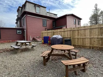 two picnic tables and a fence in front of a house at 5 Bed / 3 bath Apt Near Jiminy Peak Berkshires in Stephentown