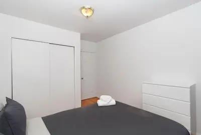 a bedroom with a black bed and white walls at The Upper East Side Monthly Rentals Apartments in New York
