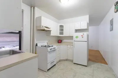 a white kitchen with a stove and a refrigerator at The Upper East Side Monthly Rentals Apartments in New York