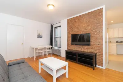 a living room with a brick wall with a tv at The Upper East Side Monthly Rentals Apartments in New York