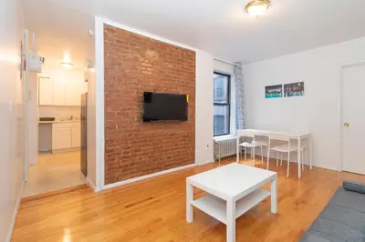 a living room with a brick wall with a tv at The Upper East Side Monthly Rentals Apartments in New York