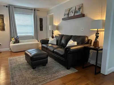 a living room with a leather couch and a chair at The Gray Horse in Saratoga Springs
