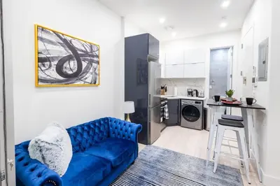 a living room with a blue couch and a kitchen at 317-1AN - New Modern 1BR W&D Walk to Central Park in New York