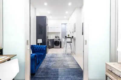 a hallway with a blue couch and a kitchen at 317-1AN - New Modern 1BR W&D Walk to Central Park in New York