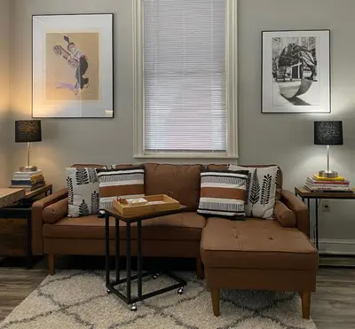 a living room with a brown couch and a window at 2 BR Loft - Walk to Cafes-Breweries- Arts & Entertainment District in Glens Falls