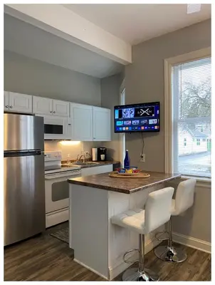 a kitchen with a refrigerator and a counter with two chairs at 2 BR Loft - Walk to Cafes-Breweries- Arts & Entertainment District in Glens Falls