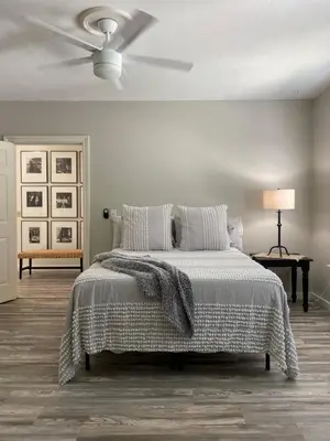 a white bedroom with a bed and a ceiling fan at 2 BR Loft - Walk to Cafes-Breweries- Arts & Entertainment District in Glens Falls