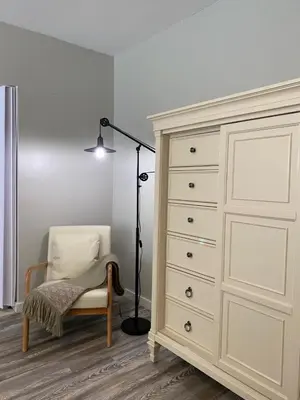 a bedroom with a dresser and a lamp and a chair at 2 BR Loft - Walk to Cafes-Breweries- Arts & Entertainment District in Glens Falls