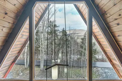 a large window in a room with a view of trees at Walk to Ski Lift! Charming Hunter A-Frame in Lanesville