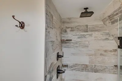 a bathroom with a walkin shower with stone walls at Walk to Ski Lift! Charming Hunter A-Frame in Lanesville