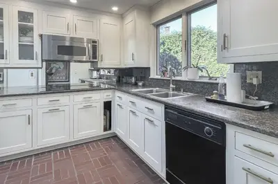 a kitchen with white cabinets and a black dishwasher at Luke's Landing in Westport