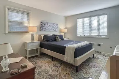 a bedroom with a bed and a table and two windows at Luke's Landing in Westport