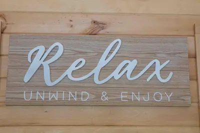a sign that says relax unlimited and enjoy on a wooden wall at Rocky Point #1 in Hamilton