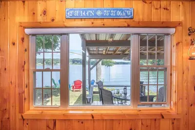 a window in a wooden cabin with a view of the water at Hamilton Home #4 in Hamilton
