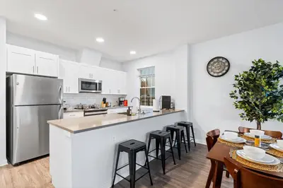 a kitchen with a refrigerator and a table with chairs at Modern 2BR 2BA Condo Sleeps 8 with Gym Laundry 20 Min to NYC in Jersey City