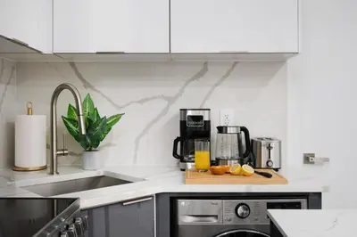 a kitchen with a coffee maker and oranges on a cutting board at 317-2A Sleek Modern 1Br UES W D in New York