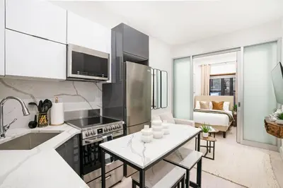 a kitchen and living room with a table and a couch at 317-1B Modern 1Br UES W D in New York