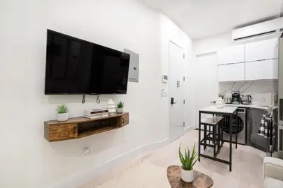 a white living room with a flat screen tv on a wall at 317-1B Modern 1Br UES W D in New York