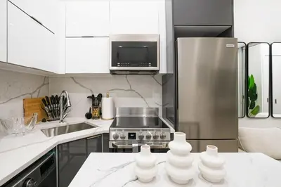 a kitchen with white cabinets and a stainless steel refrigerator at 317-1B Modern 1Br UES W D in New York