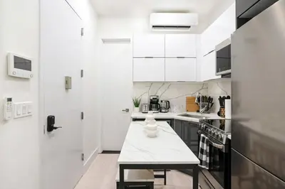 a kitchen with white cabinets and a table in it at 317-1B Modern 1Br UES W D in New York