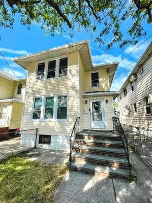 a yellow house with stairs in front of it at Entire Beautiful 2BR Private Apartment [R] in Whitestone