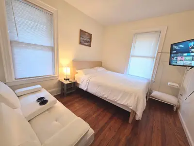 a bedroom with a bed and a couch and a tv at Entire Beautiful 2BR Private Apartment [R] in Whitestone