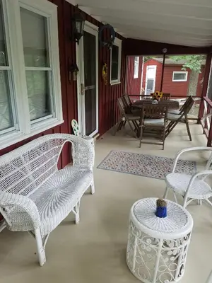 a porch with white wicker chairs and a table at Tory Hill in Hillsdale