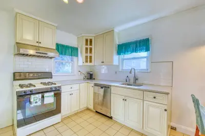a kitchen with white cabinets and a stove top oven at Family Home near NY Beach - Private Workspace in Glen Head