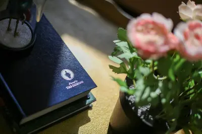 a vase with pink flowers sitting next to a book at Family Home near NY Beach - Private Workspace in Glen Head