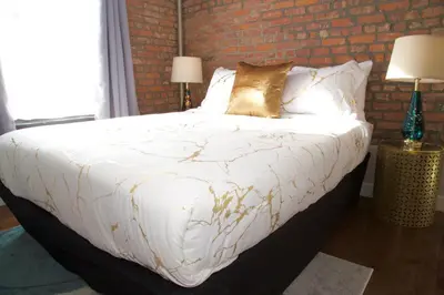 a bedroom with a white bed with a brick wall at New York Style Stay near Central Park in New York