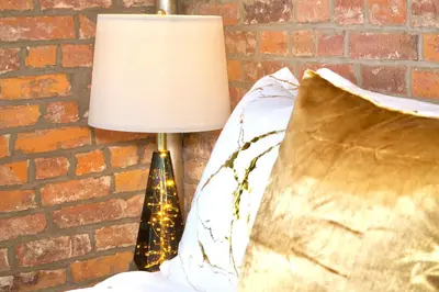a lamp sitting next to a bed with a brick wall at New York Style Stay near Central Park in New York