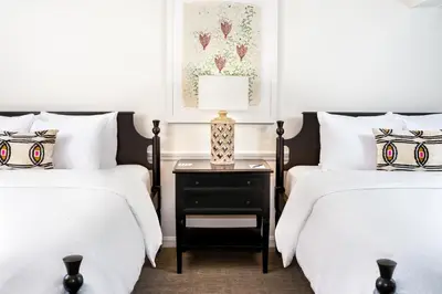 two beds with white sheets and a nightstand in a bedroom at The Ellery in Northampton