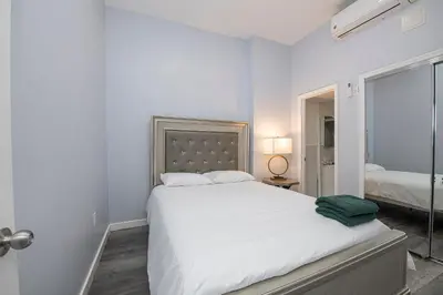 a white bedroom with a large bed and a mirror at Spectacular Times Square 5 Bedroom Duplex Oasis in New York