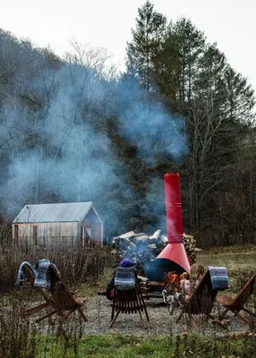 a fire in a field with a house and smoke at Eastwind Hotel Oliverea Valley in Big Indian