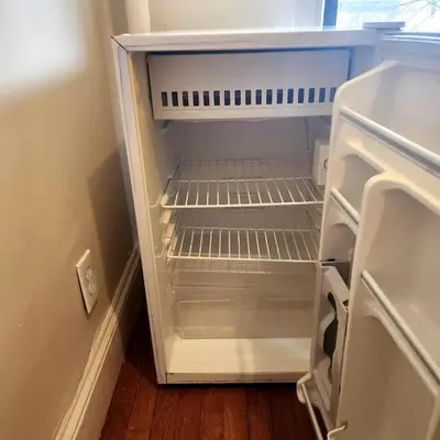 an empty refrigerator with its door open in a room at New York City Guest House in New York
