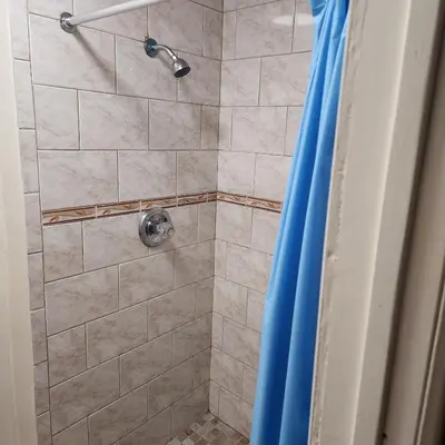 a shower with a shower head in a bathroom at New York City Guest House in New York