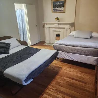 two beds in a room with a fireplace at New York City Guest House in New York