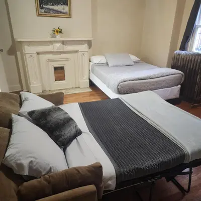 two beds in a room with a fireplace at New York City Guest House in New York