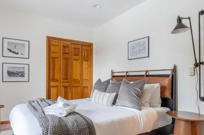 a bedroom with a white bed with a wooden headboard at 8BR Luxury Maplewood Manor, Hot Tub & Fire Pit in Jewett