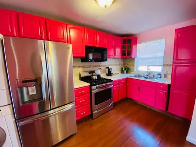 a kitchen with red cabinets and a stainless steel refrigerator at The Pink Paradise in Bronxdale