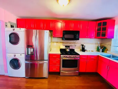 a kitchen with red cabinets and stainless steel appliances at The Pink Paradise in Bronxdale
